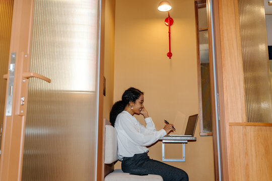 Businesswoman Working with Laptop and Phone in Office Booth