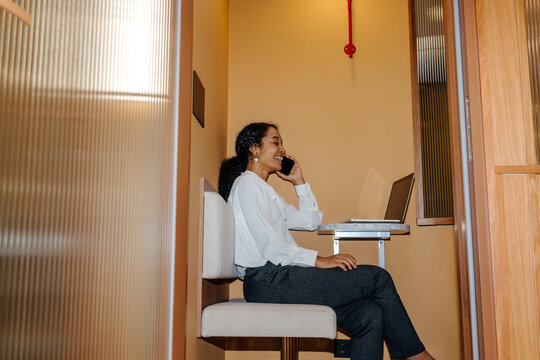 Businesswoman Talking on Smartphone in Office Privacy Booth