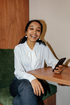 Cheerful Businesswoman Using Smartphone While Sitting at Table