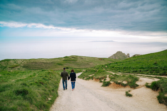Back shot of couple walking on a path to Durdle Door, Dorset in UK