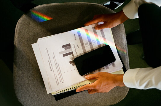 Smartphone and Documents on Office Chair with Rainbow Light Reflection