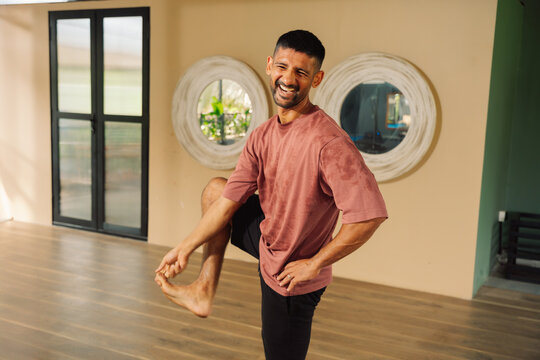 Man Stretches Leg Indoors During Workout Session in Bright Space