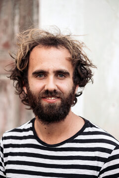 Man with beard and curly hair smiling outdoors