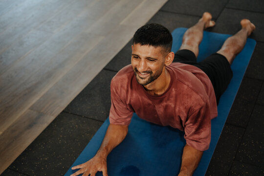 Man Exercises on Yoga Mat in a Gym During Afternoon Session
