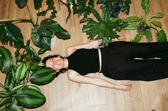 Woman lying on the floor among houseplants
