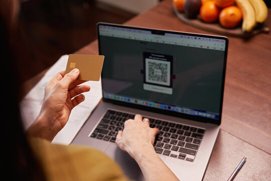Person uses card next to laptop for online shopping