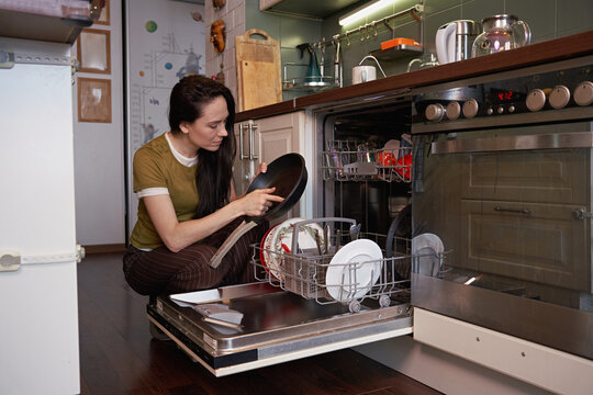 Woman washes dishes in a modern kitchen at home