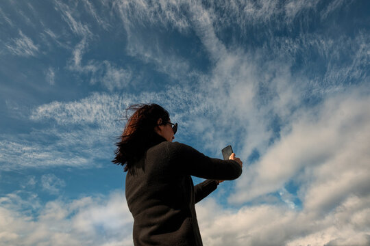 Casually Dressed Woman Taking Photos with Phone from Low Angle
