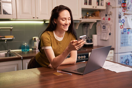 Working on a phone and laptop in a kitchen