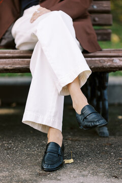 Person Sits on Bench Wearing Black Shoes and White Pants