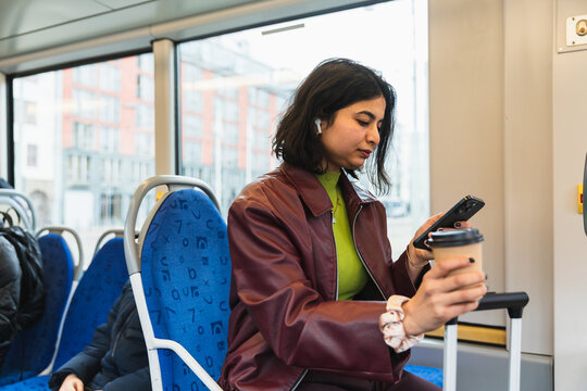 Young woman using phone while commuting on a modern city tram