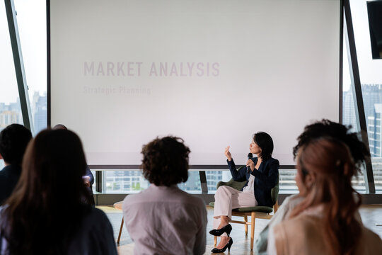 Businesswoman presents market analysis to audience in modern setting.