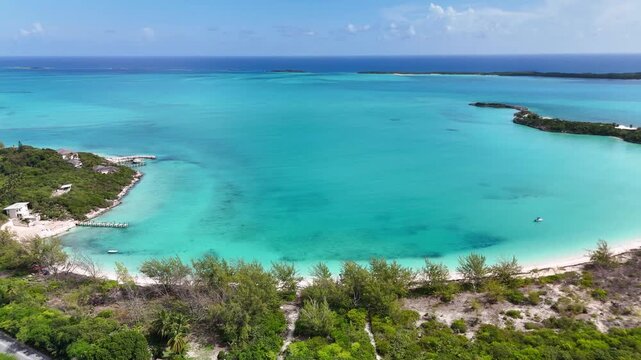 Aerial view of the turquoise waters and white sand beaches of Goat Cay with lush green vegetation and coastal villas George Town, Exuma, The Bahamas.