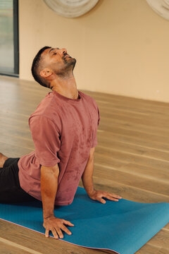Man Practicing Yoga Indoors on a Blue Mat in a Studio