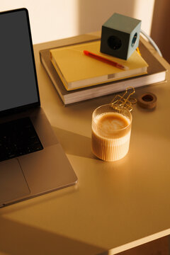 Coffee glass and laptop on desk in sunlight