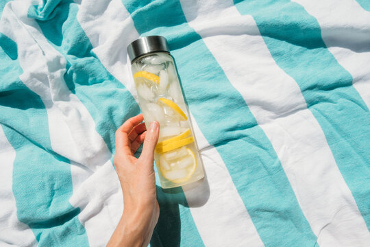 Lemon Water and Ice in Reusable Bottle on Colorful Beach Towel 