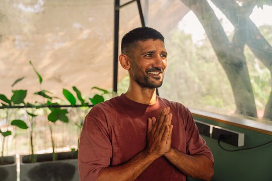 Man With Hands Together Smiling in Indoor Setting During Daytime