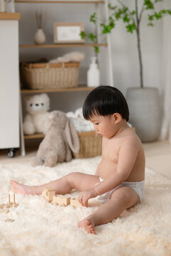 Adorable toddler playing with wooden train on fluffy rug in nursery