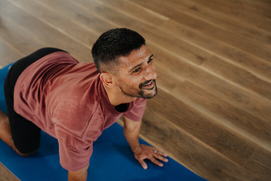 Man Practices Yoga on a Mat in a Bright Studio Space