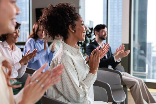 Business people applaud at a conference in a modern office.