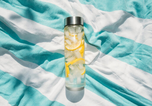 Lemon Infused Water in  Reusable Bottle on Colorful Beach Towel 