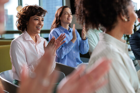 Diverse group of people clapping at a meeting.