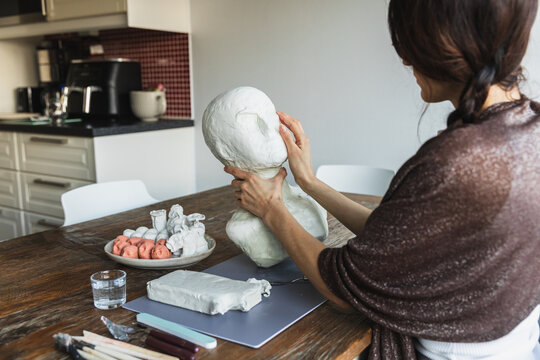 Female artist sculpting a human head bust with clay