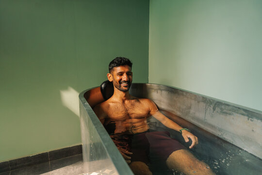Man Enjoys cold ice Bath in a Modern Tub in a Simple Room