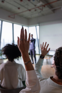 Audience members raise hands during a presentation.