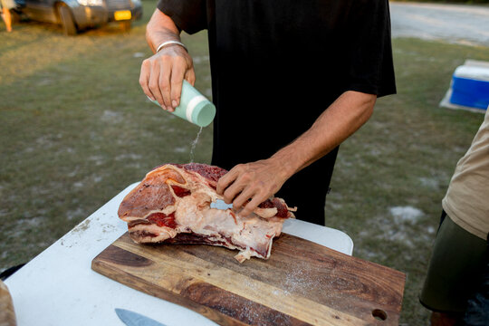 Close-up Man seasoning raw meat at campsite in Australia