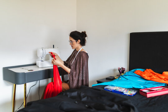 Woman using a sewing machine at home studio for fashion design.