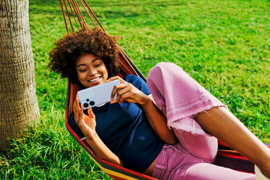 Person relaxing in hammock using smartphone outdoors