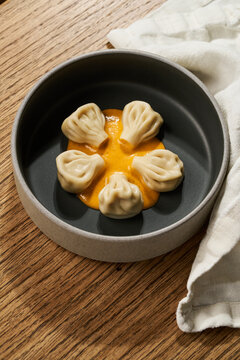 Georgian khinkali dumplings served with sauce in ceramic bowl