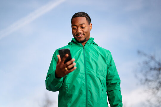 Young Black Man Using Smartphone Outdoors