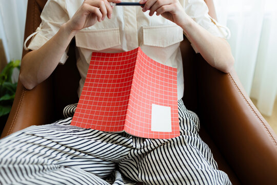 Woman Relaxing With Red Grid Notebook On Lap