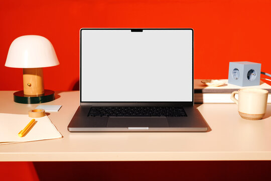 Laptop mockup with white screen on red desk