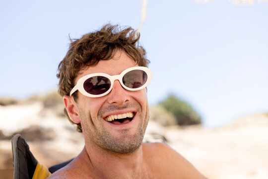 Laughing man wearing white sunglasses at the beach in Australia