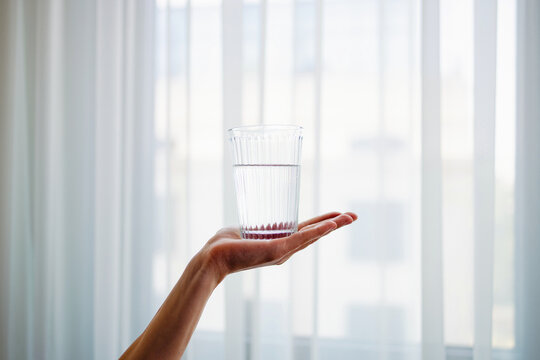 Hand Holding Glass Of Water By Window