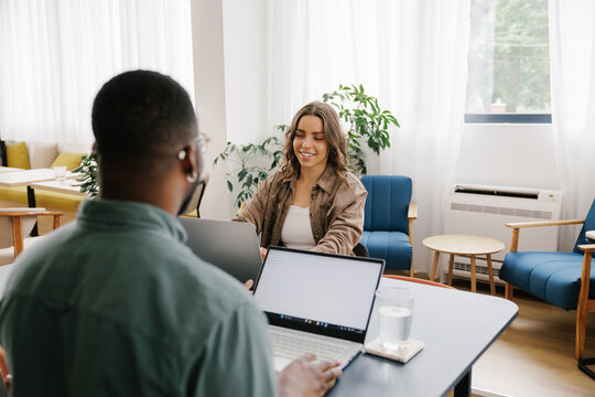 Meeting in a Modern Workspace With Two People Working on Laptops