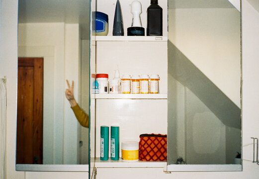 Open medicine cabinet in bathroom with meds and toiletries