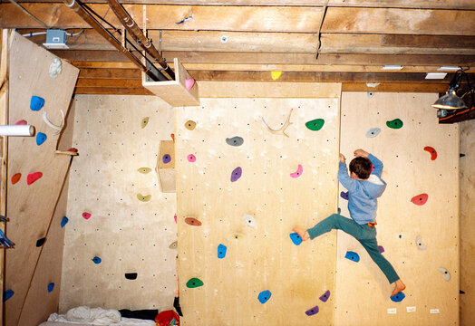 Child climbing on a DIY basement climbing wall at home