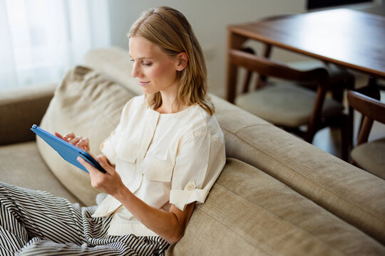 Woman Using Tablet On Couch At Home