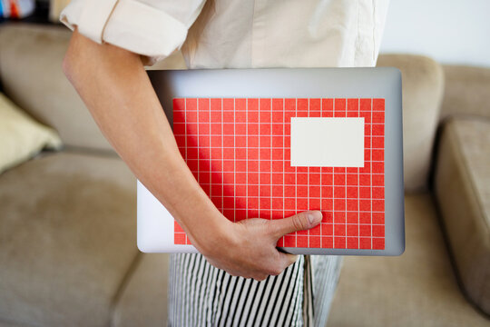 Person Holding Laptop With Red Grid Notebook 
