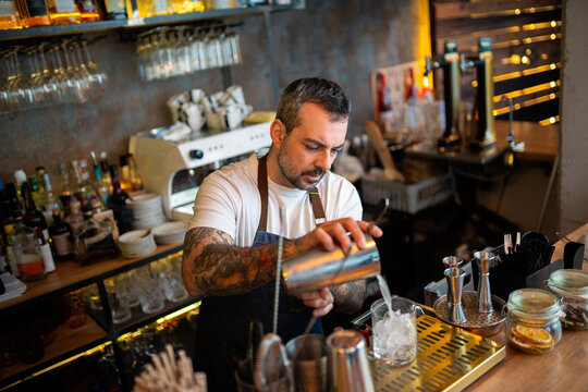 Bartender pouring cocktail from shaker into glass