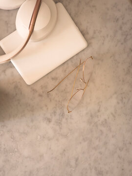 Glasses and e-Reader on a Marble Surface in a Workspace Setting