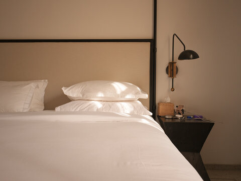 Cozy Bedroom With Clean Bed and Bedside Table in Warm Light