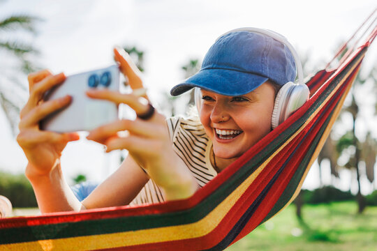 Person relaxing in hammock using smartphone and headphones