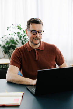 Man Working on Laptop in Modern Office Space With Plants in Background