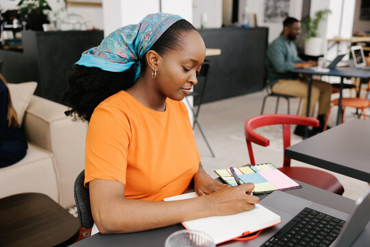 Woman Writes Notes in a Coworking Space During the Day