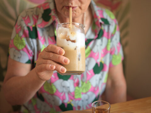 Person Enjoying Iced Coffee Drink in a Colorful Shirt